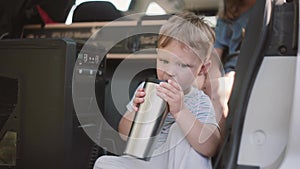 Cute little boy sitting in the car. The family moves to new apartments, carry stuffs on transport.