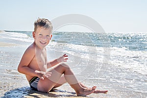 Cute little boy sitting at ocean beach