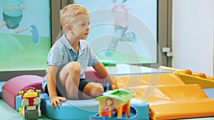 cute little boy sitting in the playroom and playing, full shot kindergarten