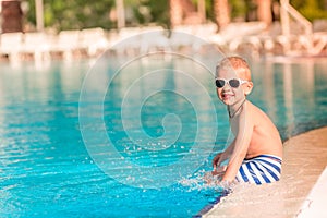 Cute little boy sitting at the pool