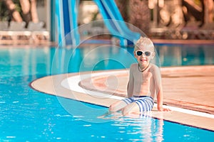 Cute little boy sitting at the pool