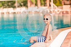 Cute little boy sitting at the pool