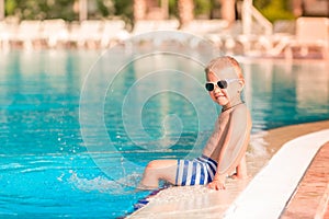 Cute little boy sitting at the pool