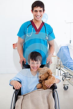 Cute little boy sitting on wheelchair and a doctor