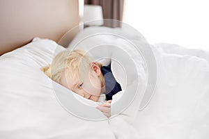 Cute little boy sleeping. Tired child taking a nap in parent`s bed.