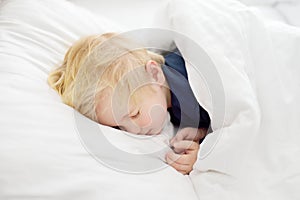 Cute little boy sleeping. Tired child taking a nap in parent`s bed.