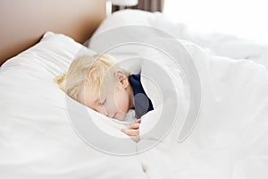 Cute little boy sleeping. Tired child taking a nap in parent`s bed.