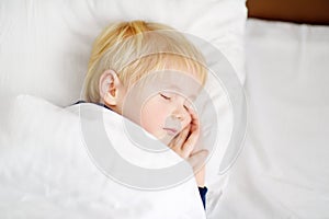 Cute little boy sleeping. Tired child taking a nap in parent`s bed.