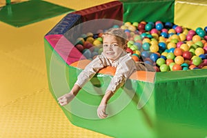 cute little boy smiling at camera while playing in pool with colorful