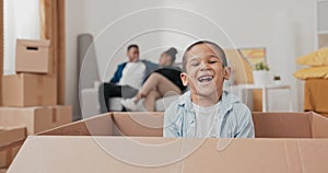 A cute little boy smiling sits in a cardboard box used for packing things during a move the child looks at his parents