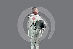 Cute little boy in space suit holding helmet and standing looking up at the sky. photo