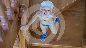 Cute little boy stands on the stairs and looks up