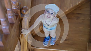 Cute little boy stands on the stairs and looks up