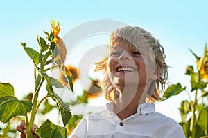 Cute little boy with sunflowers outdoors. Child spending time in nature