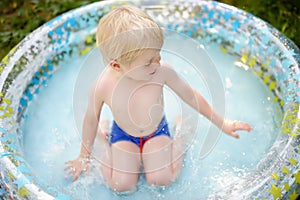 Cute little boy swimming in a inflatable pool outdoors on the backyard at sunny summer day