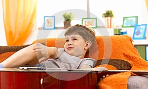 Cute little boy thinking on couch