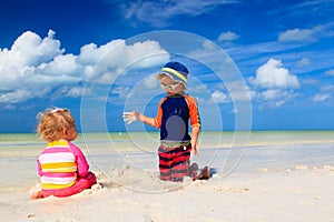 Cute little boy and toddler girl play on beach