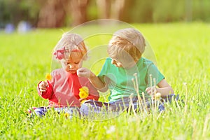 Cute little boy and toddler girl playing on green grass