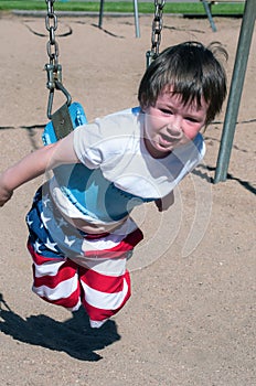 Cute little boy too short to sit in the larger swings