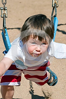 Cute little boy too short to sit in the larger swings