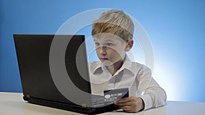 Cute little boy use laptop and credit card