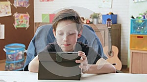 Cute little boy using digital tablet browsing the internet