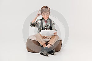 cute little boy using digital tablet and pointing up with finger