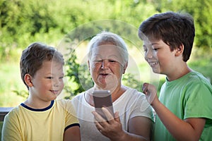 Cute little boy using smartphone with grandma at home veranda