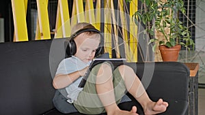 cute little boy is using tablet, viewing cartoons and playing video games online, education for kids