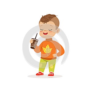 Cute little boy in warm clothing standing with cup of hot chocolate, lovely kid enjoying fall, autumn kids activity