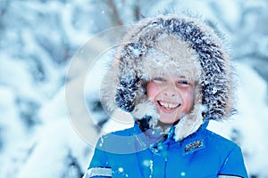 Cute little boy wearing warm clothes playing on winter forest