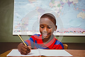 Cute little boy writing book in classroom