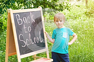 Cute little boy writting on blackboard outdoor . Back to school concept.