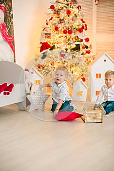 Cute little boys with blond hair plays in a bright room decorated with Christmas garlands