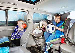 Cute little boys travelling by car in safety seats