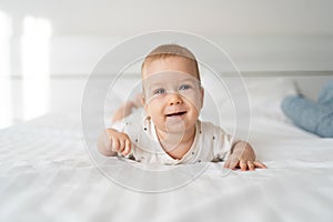 Cute little caucasian baby lies in bed. Baby care concept. Light background. Small child. cheerful emotions. 4 months