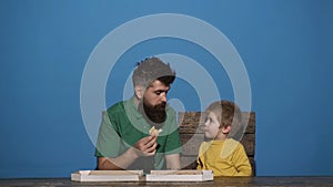 Cute little Caucasian boy and man eating pizza. Hungry child taking a bite from pizza. Delicious food. Family meal with