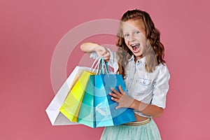 cute little caucasian child girl holds shopping bags