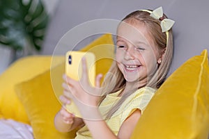 Cute little caucasian girl with blonde hair in fashionable dress illuminating yellow color sitting at home during