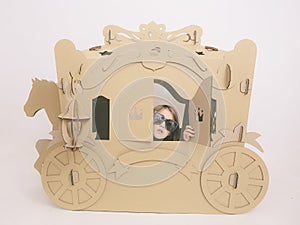 Cute Little Caucasian Girl in Pastel Pink Dress Princess Preparing for Birthday Party and posing in fairy tale carriage.