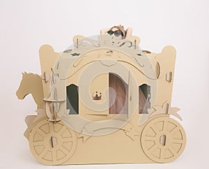 Cute Little Caucasian Girl in Pastel Pink Dress Princess Preparing for Birthday Party and posing in fairy tale carriage.