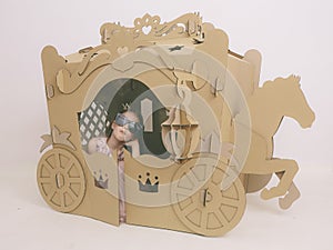 Cute Little Caucasian Girl in Pastel Pink Dress Princess Preparing for Birthday Party and posing in fairy tale carriage.