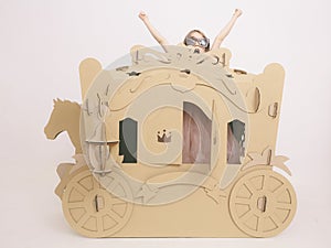 Cute Little Caucasian Girl in Pastel Pink Dress Princess Preparing for Birthday Party and posing in fairy tale carriage.