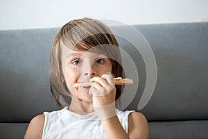 Cute little Caucasian kid eating pizza. Hungry child taking a bite from pizza on a pizza party, outdoors