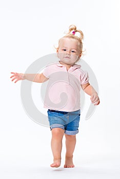 Cute little child baby girl learns to walk, make first steps isolated on a white background