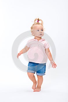 Cute little child baby girl learns to walk, make first steps isolated on a white background