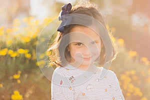Cute little child with a beautiful smile captured near the flowers in the park
