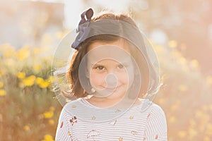 Cute little child with a beautiful smile captured near the flowers in the park