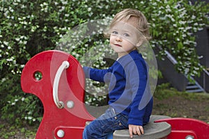 Cute little child boy having fun playing with colorful wooden toys outdoors in the park, beautiful spring sunny day in children