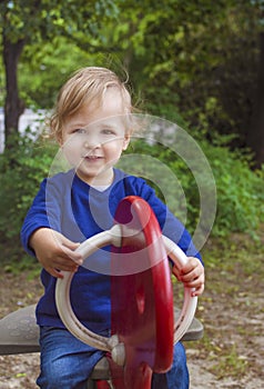 Cute little child boy having fun playing with colorful wooden toys outdoors in the park, beautiful spring sunny day in children
